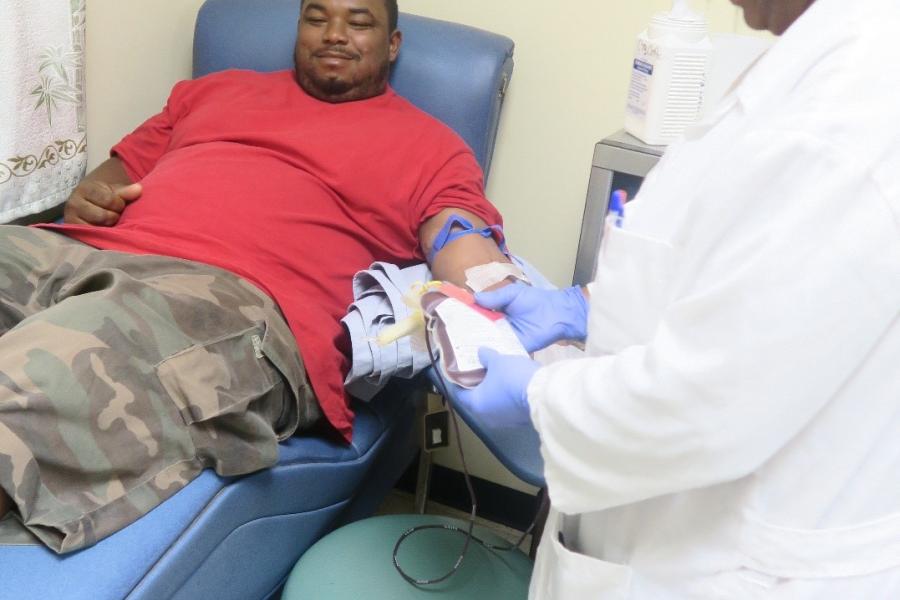Ms. Olympia Ramclam attends to a client – Mr. Lindy Cadle as he donates blood to help a sick family member.